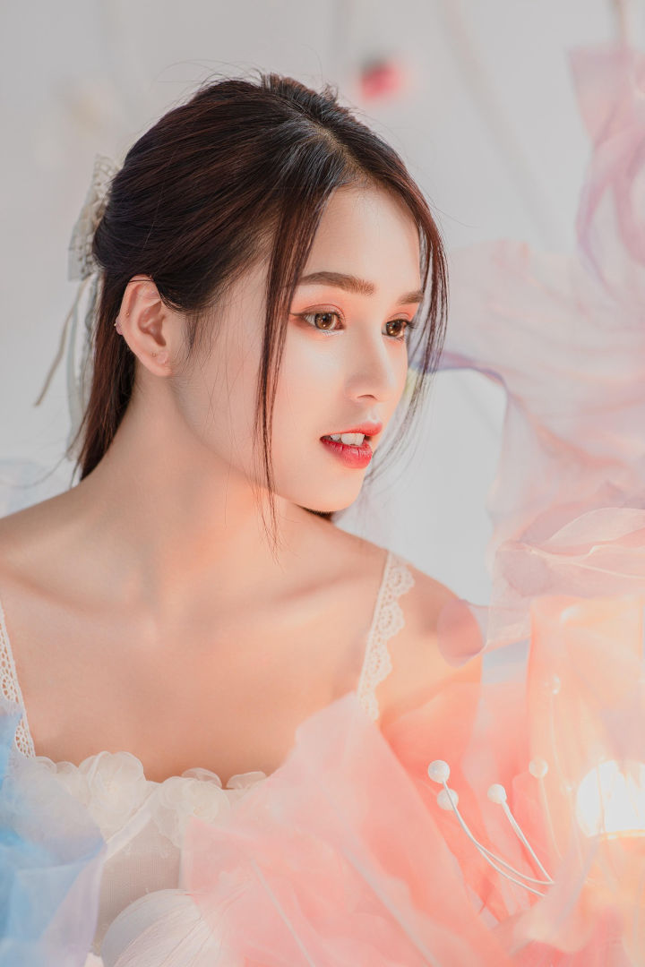 Esta imagen transmite una sensación de suavidad y luminosidad. La mujer luce una piel radiante y un maquillaje delicado, lo que la hace ideal para ilustrar el efecto de cremas hidratantes o productos de belleza. Los tonos pastel y la luz difusa refuerzan la idea de pureza y cuidado de la piel, elementos clave en la promoción de cosméticos premium.